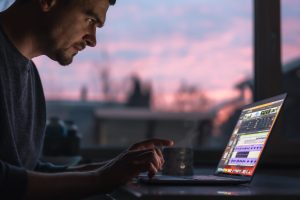 A male musician, arranger works with sound on a laptop in the dark early in the morning.